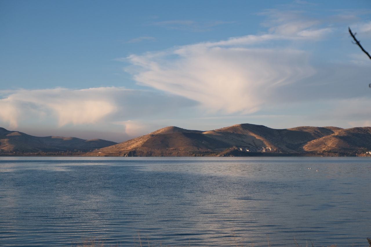 Tranquil landscape with mountains reflecting on a calm lake under a clear sky.